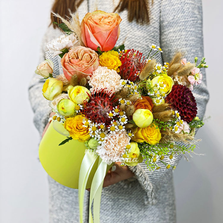 Желтая коробка с розами, протеями и заленью (в руках флориста)